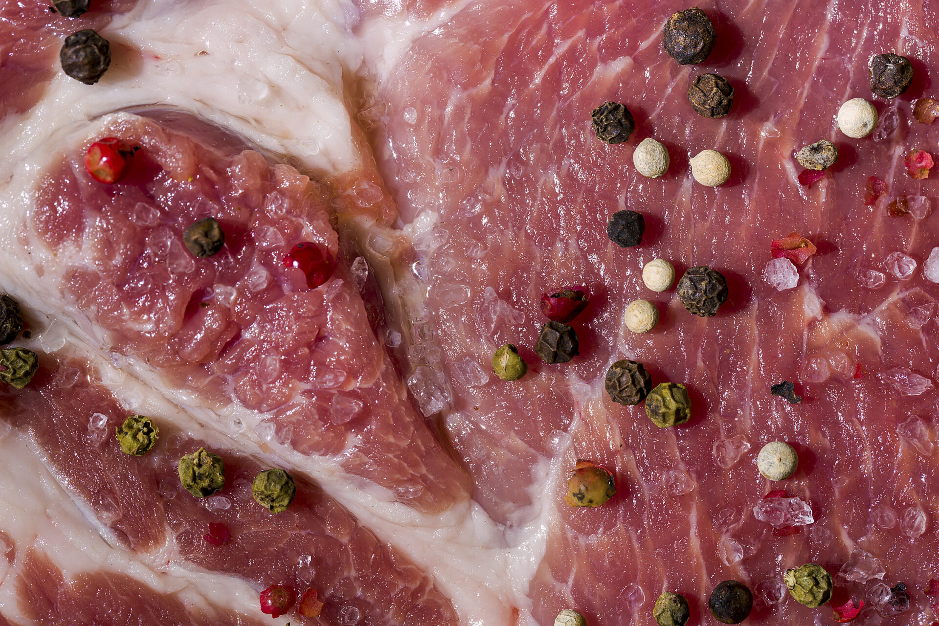 Raw beef meat with salt and peppercorns, close-up. Horizontal orientation