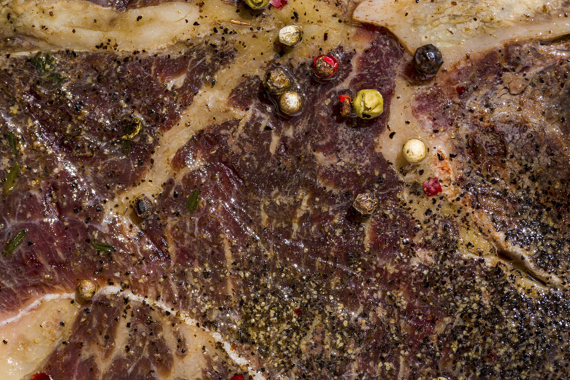 Beef meat on the bone with rosemary, and peppercorns close-up. Horizontal orientation